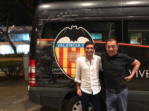 Marcelino y Peter Lim, junto a un microbús con el escudo