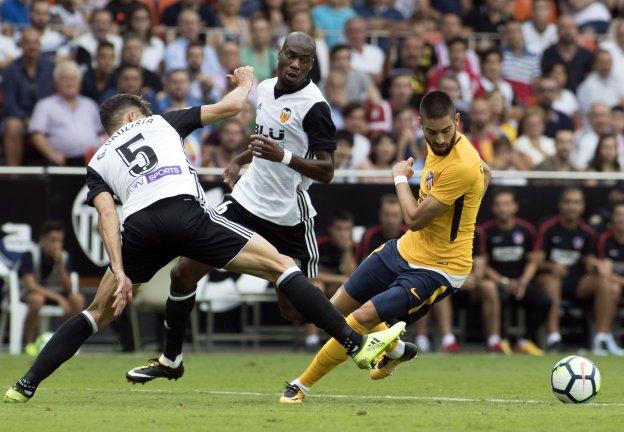 Paulista y Kondogbia contra Carrasco durante el Valencia-Atlético de Madrid. / AFP PHOTO/JAIME REINA