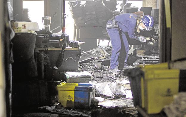 Una policía examina los restos del incendio de uno de los juzgados de la Ciudad de la Justicia. / Damián torres