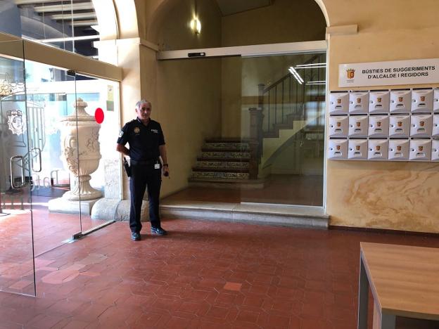 Uno de los accesos acristalados instalado en el edificio consistorial, junto a un agente. / lp