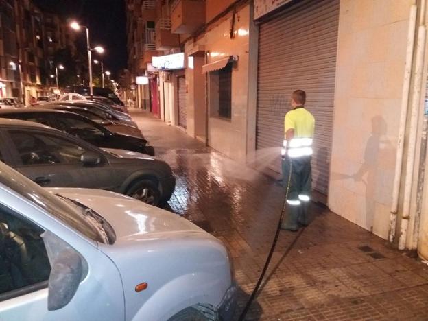 Un operaro baldea una calle de Torrent. / lp