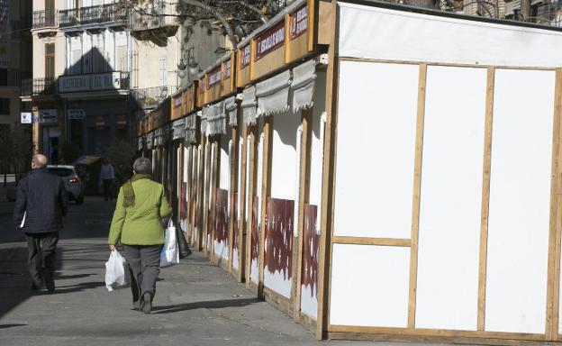 Viandantes pasean por la calzada entre las casetas vacías. / damián torres