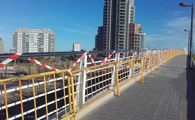 Vallas con bridas de plástico protegen la barandilla de la pasarela que une Nazaret y la Ciudad de las Artes. /LP