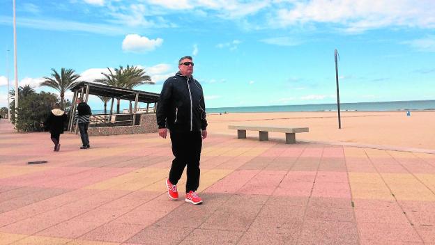 Un turista camina ayer por el paseo marítimo de la playa de Gandia ante las buenas temperaturas. / ó.d.