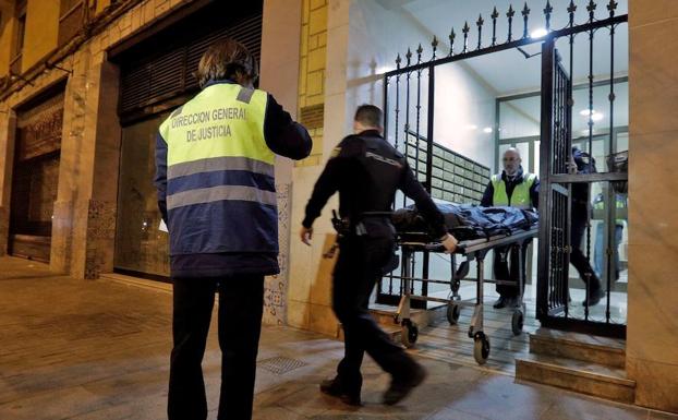 Miembros del retén fúnebre y agentes del Cuerpo Nacional de Policía retiran los restos humanos hallados en el interior de una vivienda de Benimaclet. /EFE