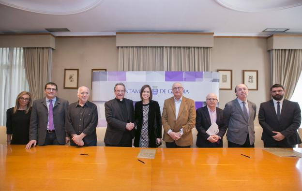 El vicario Vicente Fontestad y la alcaldesa de Gandia, Diana Morant, en el centro, se dan la mano, ante representantes de la UPV, el Arzobispado y el ejecutivo. / àlex oltra