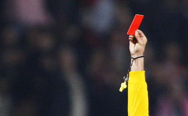 Un árbitro muestra una tarjeta roja en un partido./Reuters