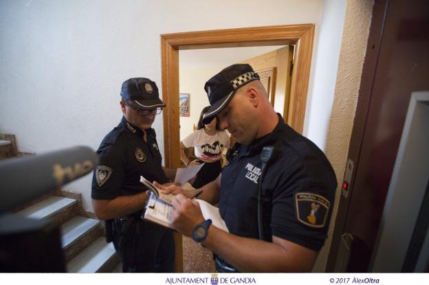 Agentes de la Policía Local de Gandia comprueban los datos de una vivienda durante una inspección efectuada el verano pasado. / àlex oltra