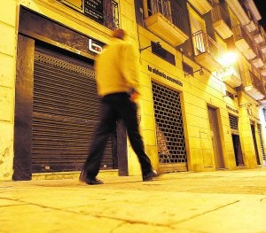 Un viandante pasa por delante de la persiana cerrada del pub donde ocurrieron los hechos, ayer. :: Á. DOMÍNGUEZ/