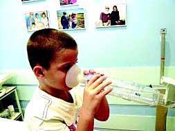 Un niño aplicándose una medicación inhalada mediante cámara./