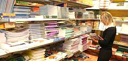 Una joven revisa los libros de texto que se exponen en las estanterías de un centro comercial./