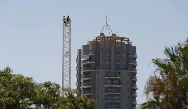 Operarios en lo alto de una grúa en proceso de montaje para la construcción de un edificio en Valencia. / JUAN J.MONZO