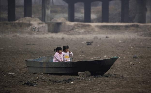 Dos niÃ±as juegan en una barca abandonada en un lago seco en Zhengzhou, en la provincia china de Henan./REUTERS