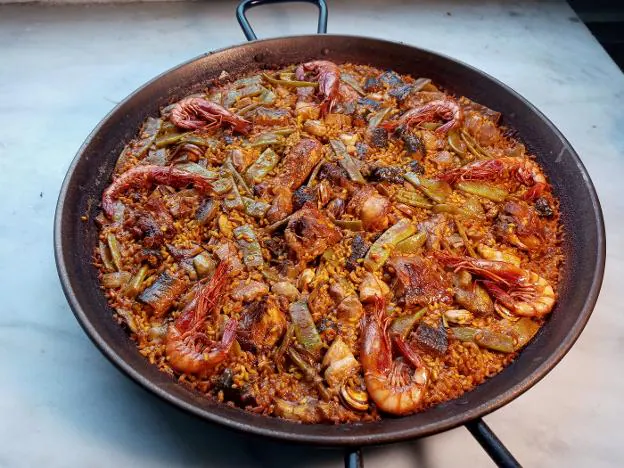 Paella valenciana tal ycomo se cocinaba haceun siglo. Debajo, reedición del recetario del arroz. Aceitunas entrando en la almazara. lp/ LP