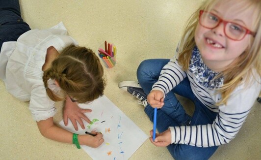 Una niña con trisomía 21 dibuja junto a una compañera sin discapacidad. /DOWN ESPAÑA