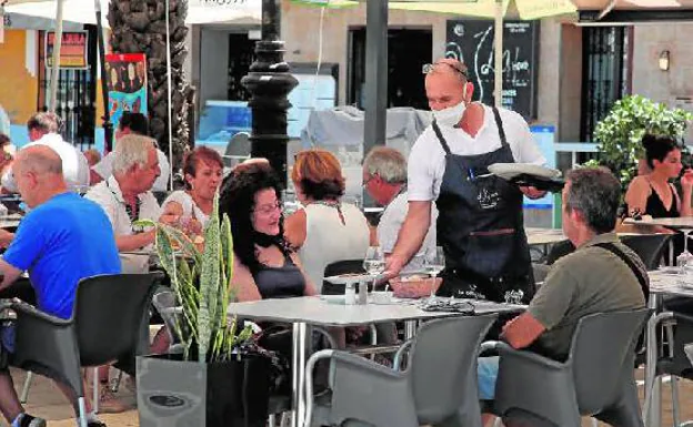 Un camarero sirve comida a los clientes en la terraza de un restaurante de Dénia.