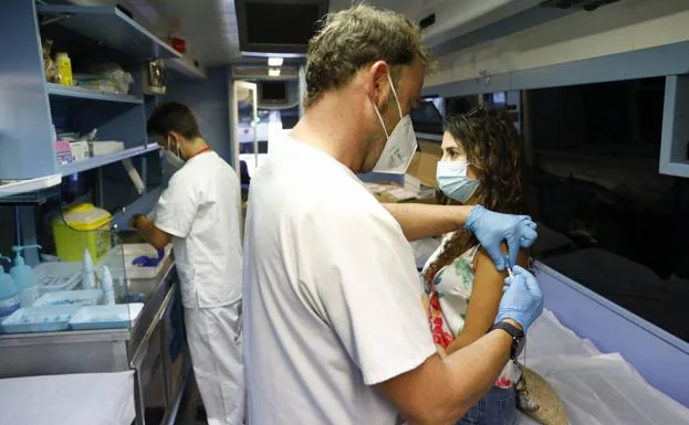 Una mujer joven es vacunada en una estación móvil de vacunación de Valencia.