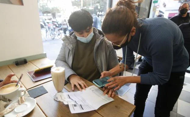 Un empleado de una cafetería escanea los pasaportes Covid de los clientes.