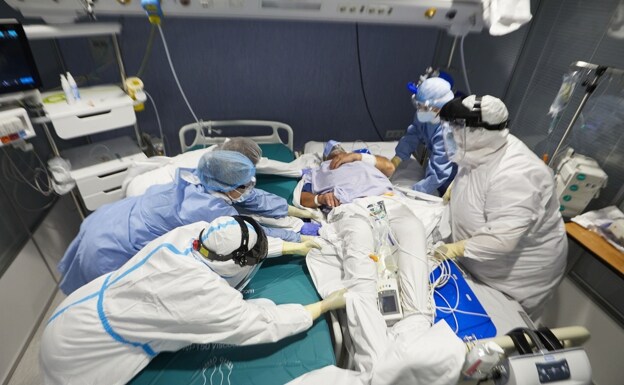Varios profesionales sanitarios tratan a un paciente ingresado por Covid en una unidad de cuidados intensivos en Arnau de Vilanova./ IVÁn Arlandis