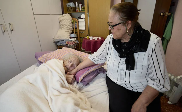 Lourdes toma la mano de Felisa, su madre que tiene más de cien años. 